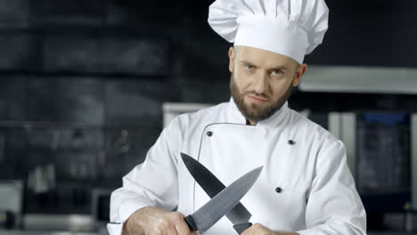 Männlicher-Koch-Posiert-Mit-Gekreuzten-Messern.-Koch-Schärft-Messer-In-Der-Küche.