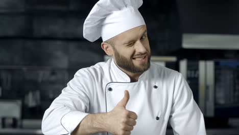 Chef-Hombre-Posando-En-La-Cocina-Profesional.-Chef-Profesional-Con-Los-Pulgares-Hacia-Arriba