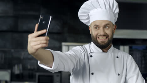 Chef-Profesional-Posando-En-La-Cocina.-Chef-Haciendo-Una-Foto-Selfie-Con-Un-Teléfono-Móvil