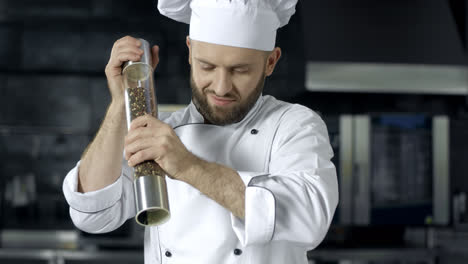 Chef-man-cooking-at-kitchen-restaurant.-Male-chef-peppering-food-at-kitchen.
