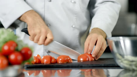 Chef-male-cutting-tomato-at-restaurant-kitchen.-Closeup-chef-cooking-fresh-food.