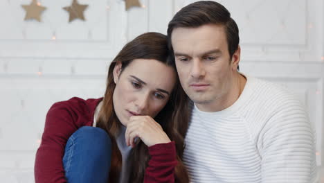 Portrait-of-thinking-couple-sitting-in-living-room.-Sad-lady-lying-man-shoulder