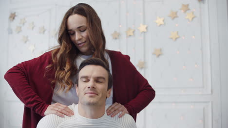 Relaxed-couple-massaging-in-living-room.-Smiling-woman-making-massage