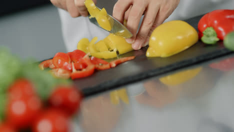 Male-chef-cooking-fresh-food-at-kitchen-restaurant.-Closeup-hands-slicing-pepper