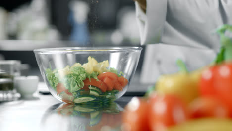 Chef-peppering-salad-at-kitchen-restaurant.-Closeup-hands-peppering-vegetables.