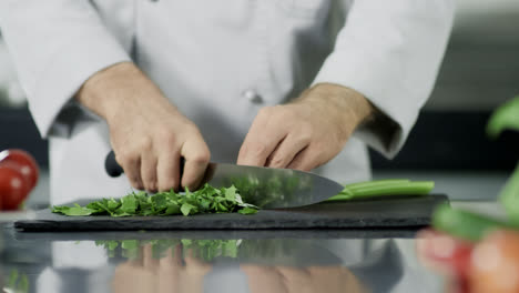 Chef-hands-cutting-celeriac-at-kitchen.-Closeup-chef-hands-cooking-greenery.