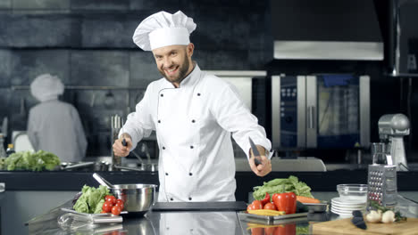 Chef-man-making-fun-at-kitchen-restaurant.-Smiley-male-chef-posing-with-knives.