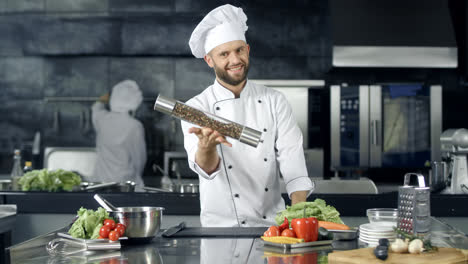 Smiling-chef-playing-with-pepperbox-at-workplace.-Happy-worker-preparing-to-cook