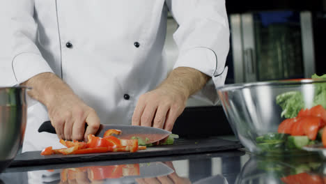 Chef-cooking-vegetables-at-kitchen.-Closeup-hands-cutting-organic-food