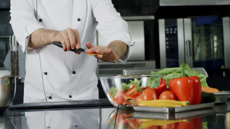 Chef-cooking-salad-at-kitchen.-Chef-hands-putting-fresh-vegetables-in-glass-bowl