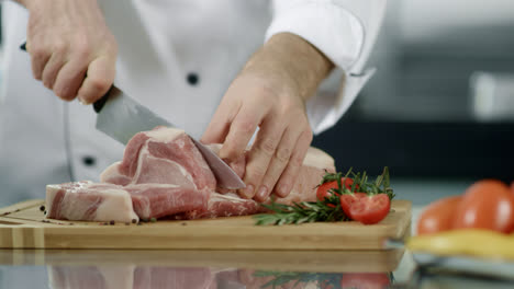 Chef-hands-cutting-meat-at-kitchen.-Closeup-man-chef-hands-cutting-pork-fillet