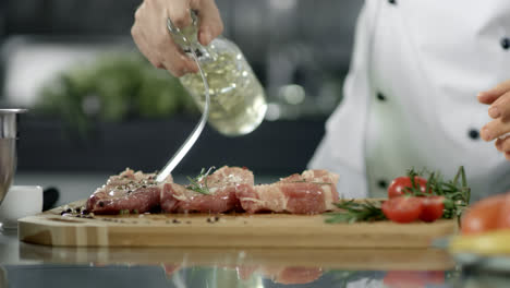 Chef-cooking-raw-steak-at-kitchen-restaurant.-Chef-oiling-pork-fillet