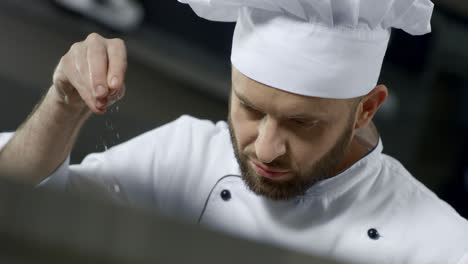 Portrait-of-chef-salting-food-at-kitchen.-Chef-cooking-food-in-slow-motion