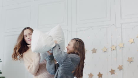 Closeup-mom-and-daughter-throwing-pillows-on-bed-in-in-luxury-bedroom.