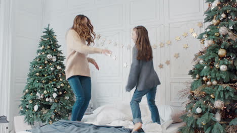 Cheerful-mother-and-daughter-having-dance-party-on-bed-in-luxury-house.