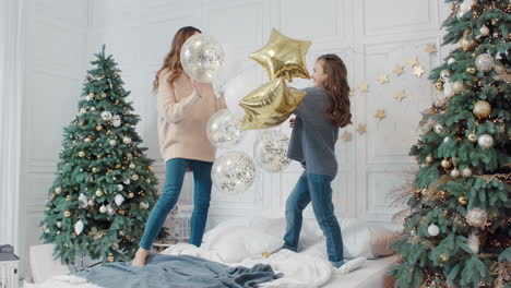 Happy-ladies-playing-with-star-balloons-on-bed-in-private-house.