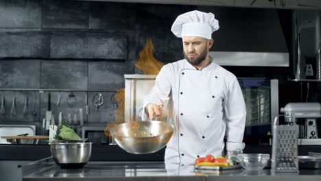 Professional-chef-throwing-food-in-pan-with-burning-flame-at-kitchen