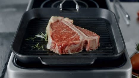 Frisches-Steak,-Das-In-Der-Grillpfanne-Zubereitet-Wird.-Nahaufnahme-Von-Rindfleisch,-Das-Mit-Rosmarin-In-Der-Pfanne-Kocht.