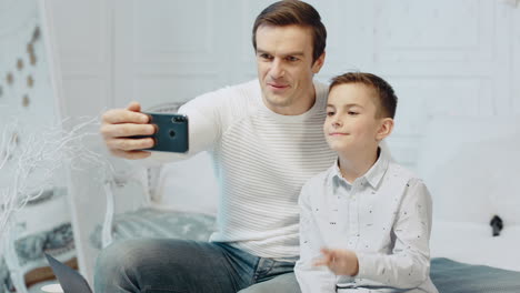 Smiling-father-and-son-making-selfie-in-luxury-house-together.
