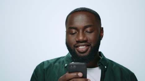 Portrait-of-smiling-african-american-man-using-smartphone-on-grey-background.