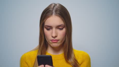 Portrait-of-upset-attractive-woman-using-smartphone-on-grey-background.
