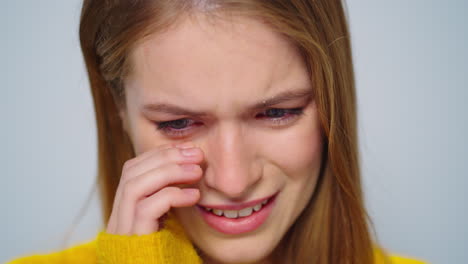 Closeup-attractive-woman-crying-at-camera-on-grey-background-in-studio.