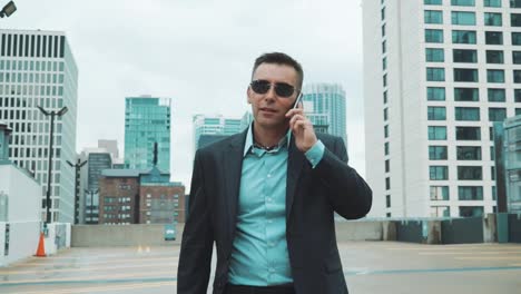 Young-man-in-suit-talking-on-phone-in-city.-Handsome-businessman-in-suit