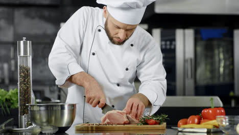 Male-chef-cutting-meat-slice-at-professional-kitchen.-Chef-preparing-beef