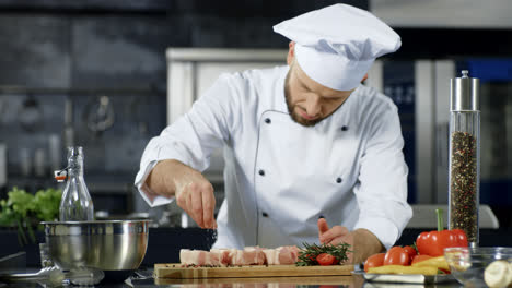 Male-chef-salting-meat-in-slow-motion-at-kitchen.-Professional-man-cooking-dish