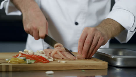 Chef-hands-cutting-meat-at-kitchen.-Closeup-chef-hands-cutting-chicken-fillet