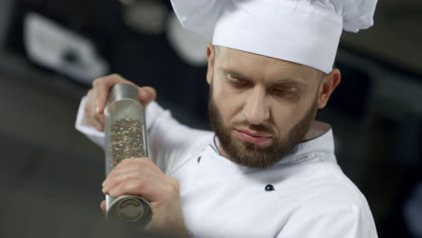 Portrait-of-chef-cooking-at-kitchen.-Closeup-chef-peppering-food-in-slow-motion.