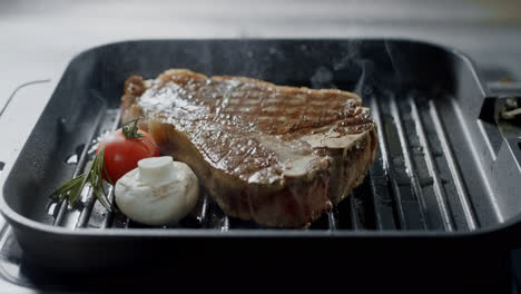 Grill-meat-frying-at-griddle.-Closeup-steak-with-vegetables-cooking-at-grill.