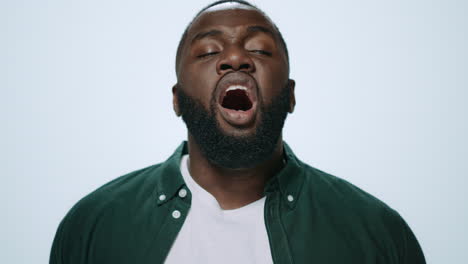 Close-up-sick-african-american-man-sneezing-on-grey-background-in-studio.