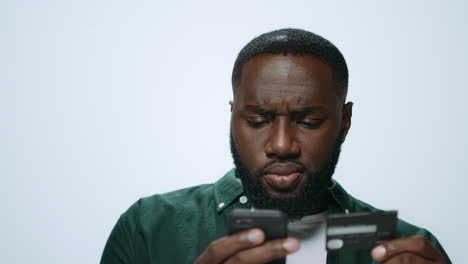 Portrait-of-serious-african-man-shopping-online-on-smartphone-in-studio