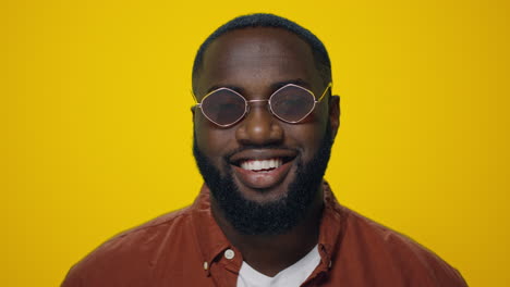 Portrait-of-african-american-man-smiling-at-camera-on-yellow-background.