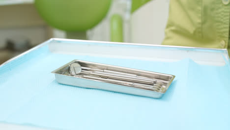 Dentist-hands-unpacking-dentistry-tools.-Dental-mirror-and-probe-in-steel-plate