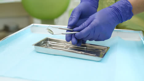 Stomatolog-holding-dental-mirror-and-probe.-dentist-hands-taking-dentistry-tools