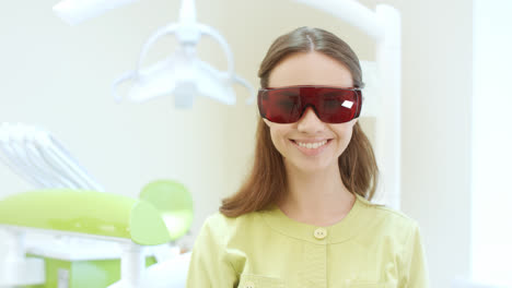 Female-dentist-dressing-up-ultraviolet-orange-safety-goggles.-Woman-doctor