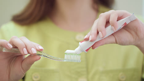 Doctor-hands-squeezing-toothpaste-on-toothbrush.-Morning-teeth-care-concept