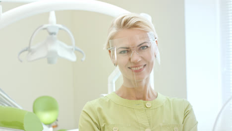 Female-dentist-dressing-up-safety-glasses.-Woman-doctor-preparing-for-work