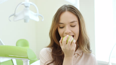 Mujer-Feliz-Comiendo-Manzana-En-La-Clínica-Dental.-Paciente-Sonriente-En-El-Consultorio-Del-Dentista.