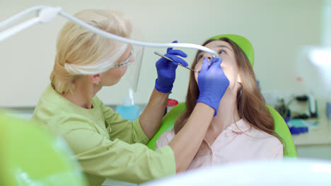 Woman-dentist-drilling-tooth-of-patient-in-dental-office.-Doctor-and-patient