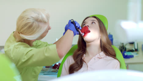 Estomatólogo-Que-Utiliza-Lámpara-De-Polimerización-Dental-Para-La-Cavidad-Bucal.-Dentista-Y-Paciente