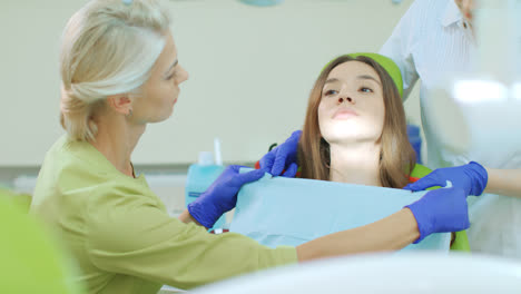 Dentist-with-assistant-preparing-for-dental-treatment.-Patient-in-dentist-chair