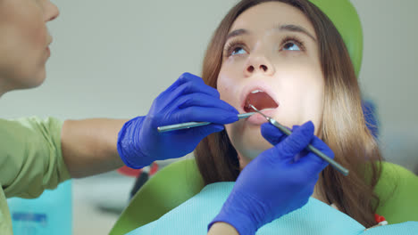Nahaufnahme-Der-Hände-Des-Zahnarztes,-Der-Die-Zähne-Des-Patienten-Mit-Dem-Mundspiegel-Untersucht