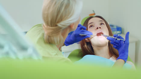 Dentist-doing-anesthesia-of-young-woman.-Female-dentist-using-mouth-mirror
