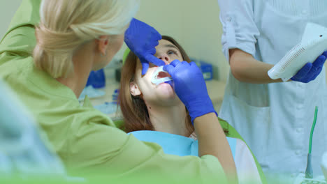 Dentista-Con-Asistente-Preparando-A-Una-Niña-Para-Blanquear-Los-Dientes.-Procedimiento-De-Blanqueamiento