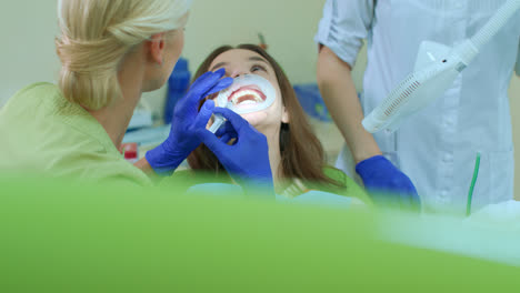 Professional-whitening-teeth-procedure-in-dental-office.-Dentist-with-assistant