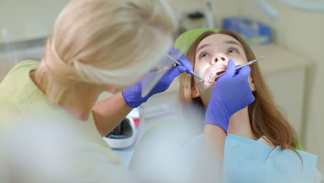 Dentist-examining-patient-teeth-in-medical-gloves.-Dental-curing-of-patient