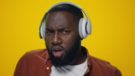 Portrait-of-happy-african-man-dancing-in-headphones-on-yellow-background.